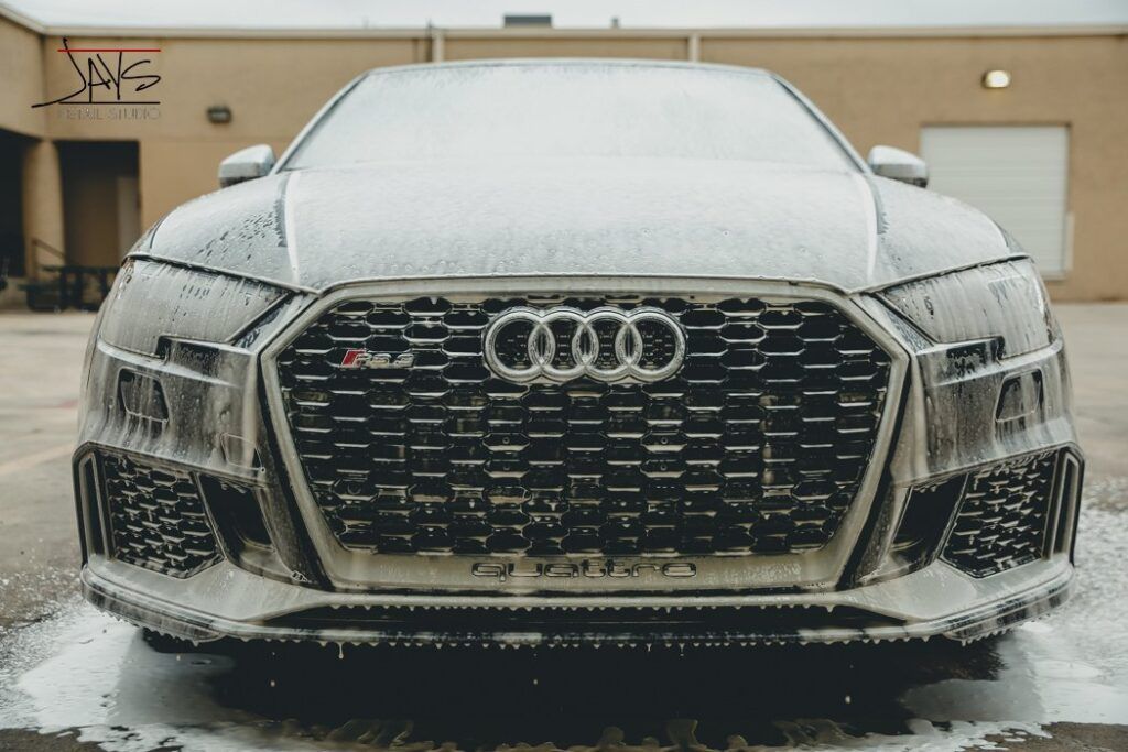 Black Audi RS3 covered in white foam during a car wash.