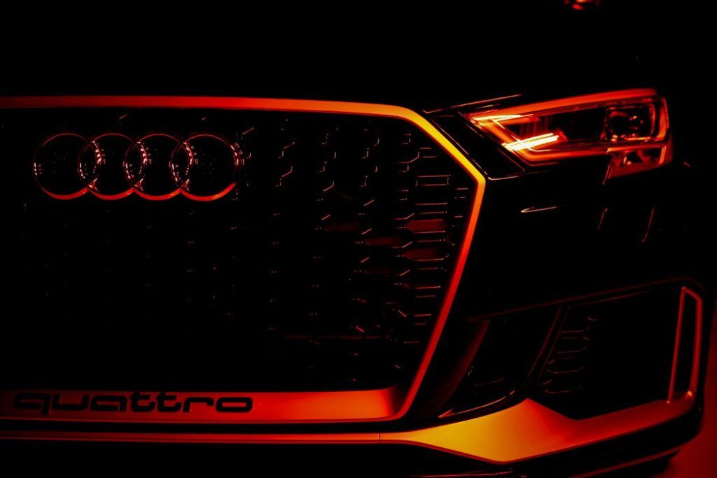 Audi car front grill, illuminated with red/orange light, Quattro emblem.