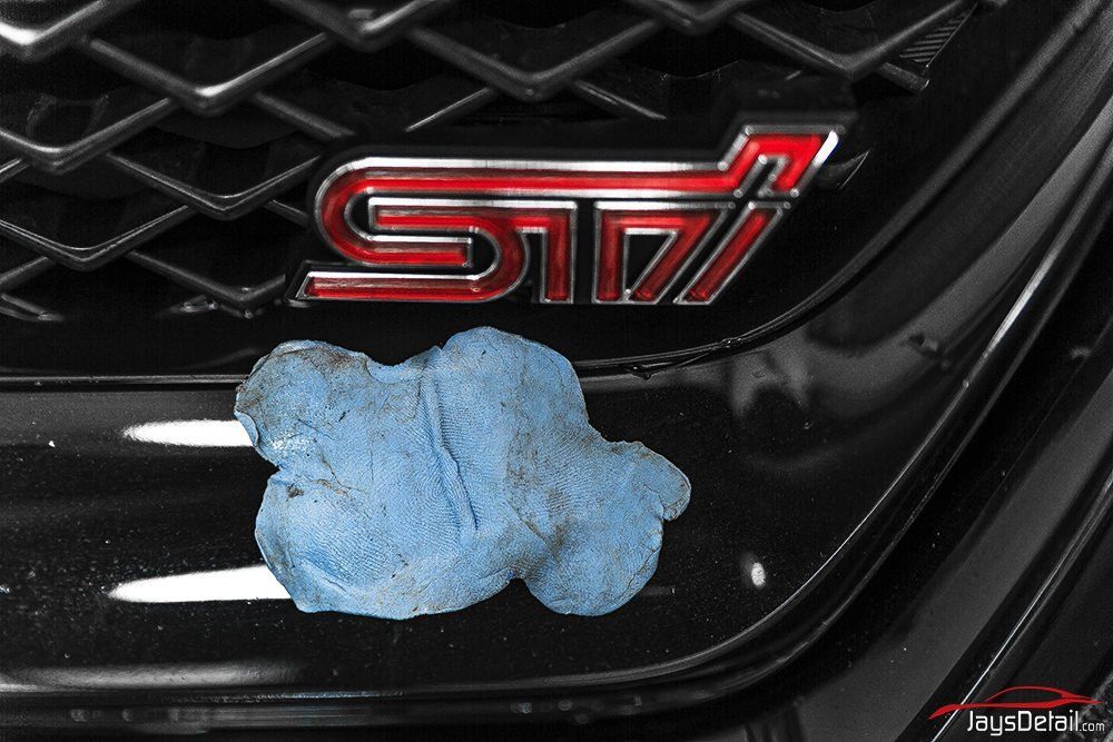 Blue clay on black car grill with red