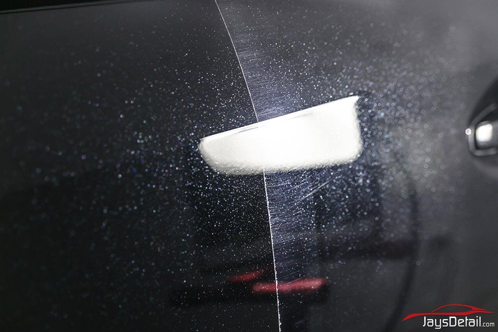 Car door half polished, showing before-and-after difference; shiny dark paint on left, hazy on right.