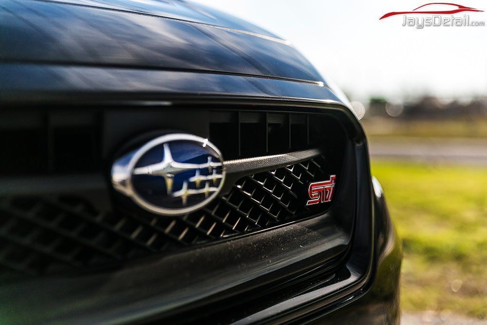 Close-up of a black Subaru WRX STI grille with the Subaru logo and STI badge.
