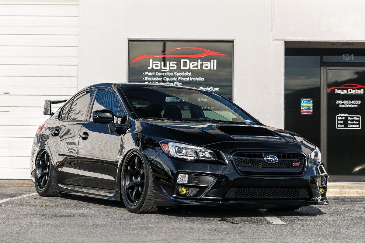 Black Subaru WRX with yellow fog lights parked outside