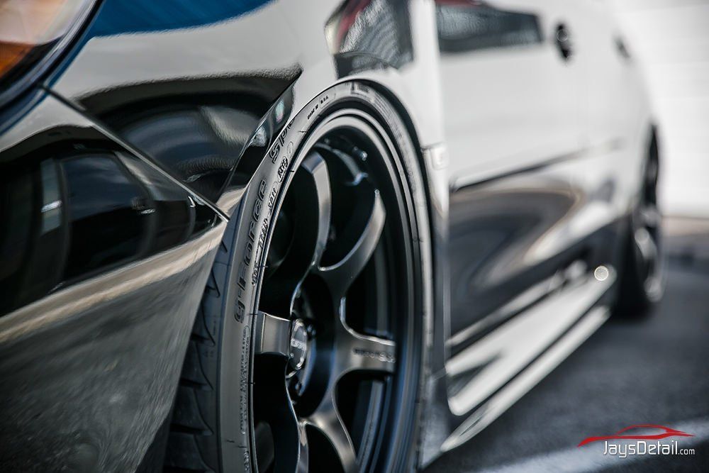Black car wheel close-up with shiny paint, angled view showing the tire and rim.