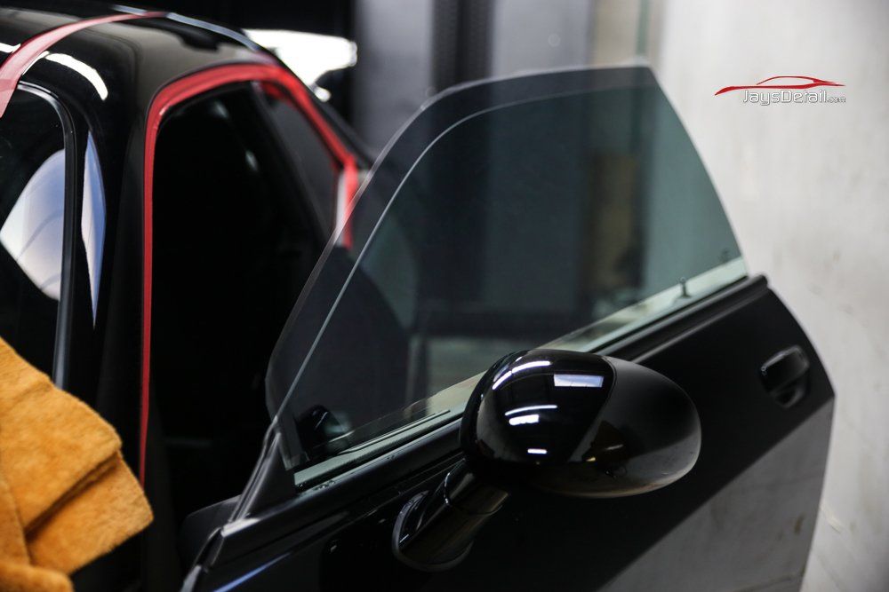 Black car door open, tinted window, black side mirror.