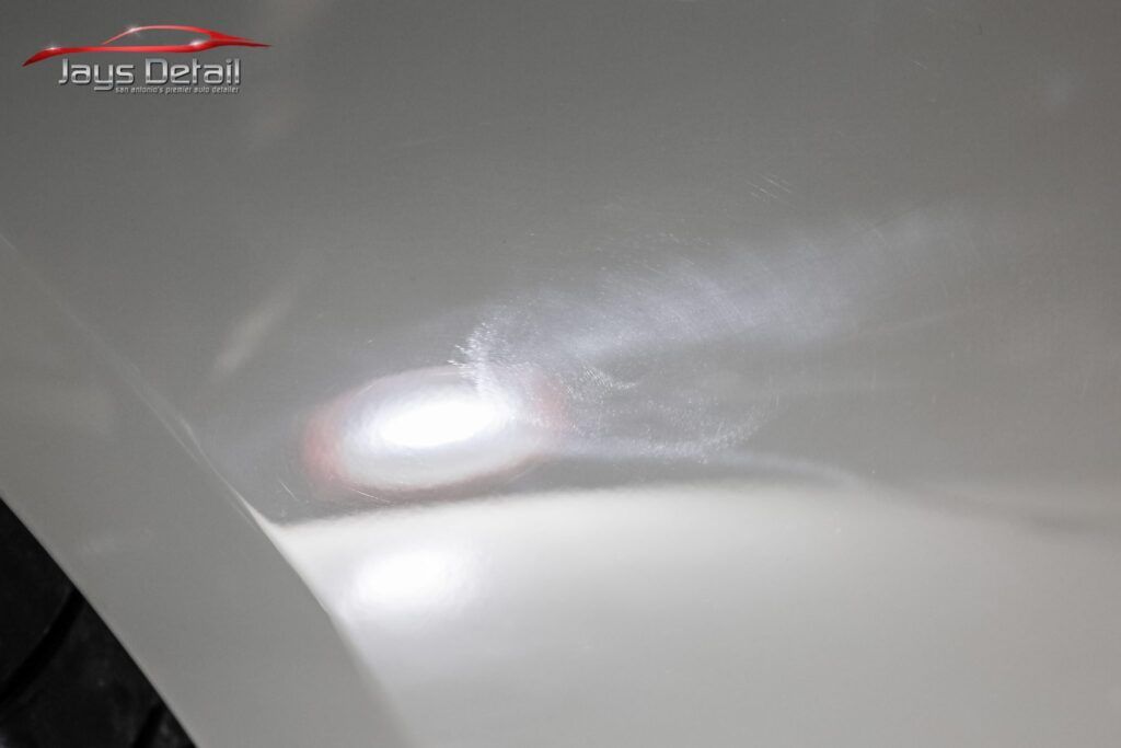 Windshield of a black car being treated with window tinting film; film is wet and translucent.