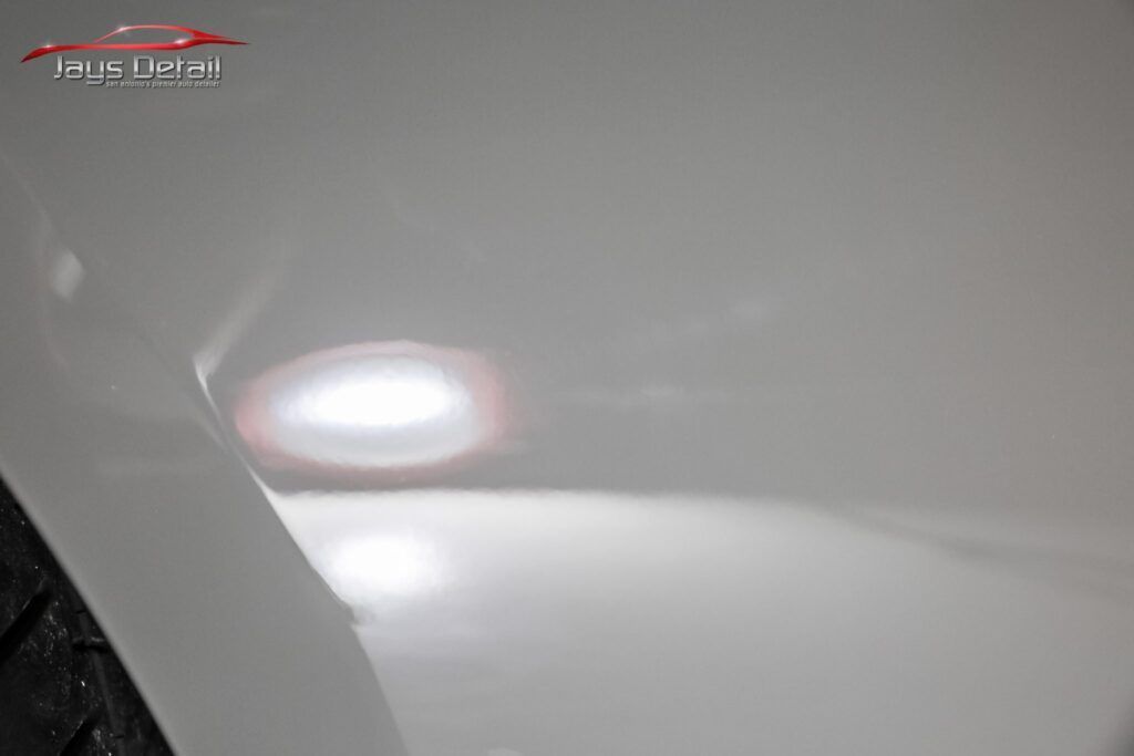 White car body with a dent, reflecting light.