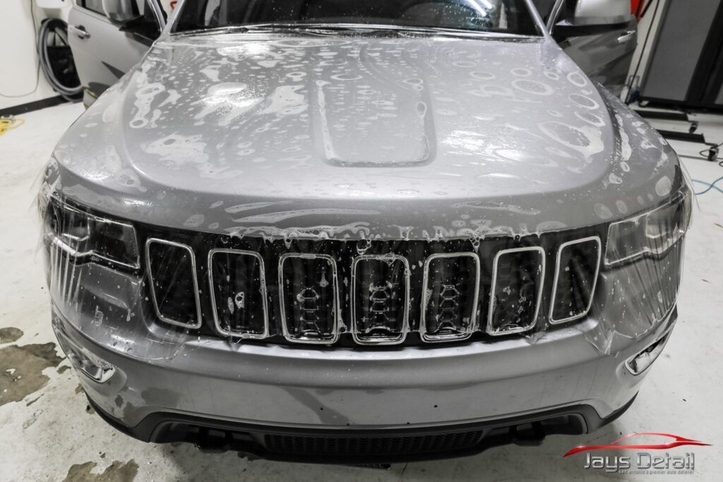 Gray Jeep Grand Cherokee being cleaned, covered in soap.