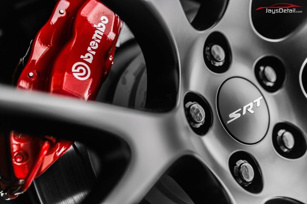 Red Brembo brake caliper and SRT wheel close-up in grayscale.