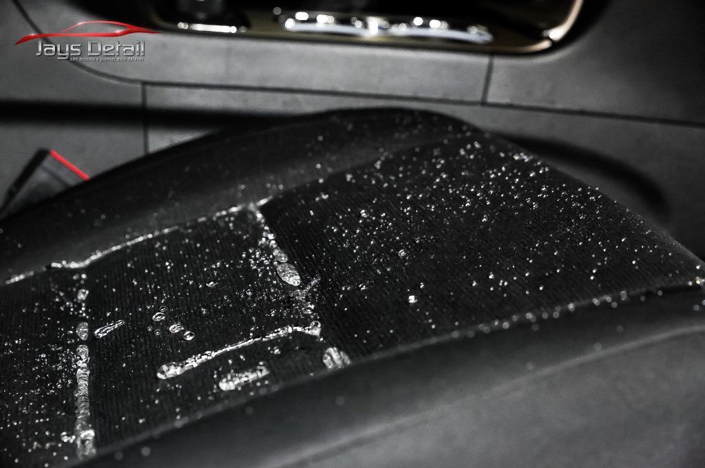 Close-up of a damaged black car seat with peeling surface.