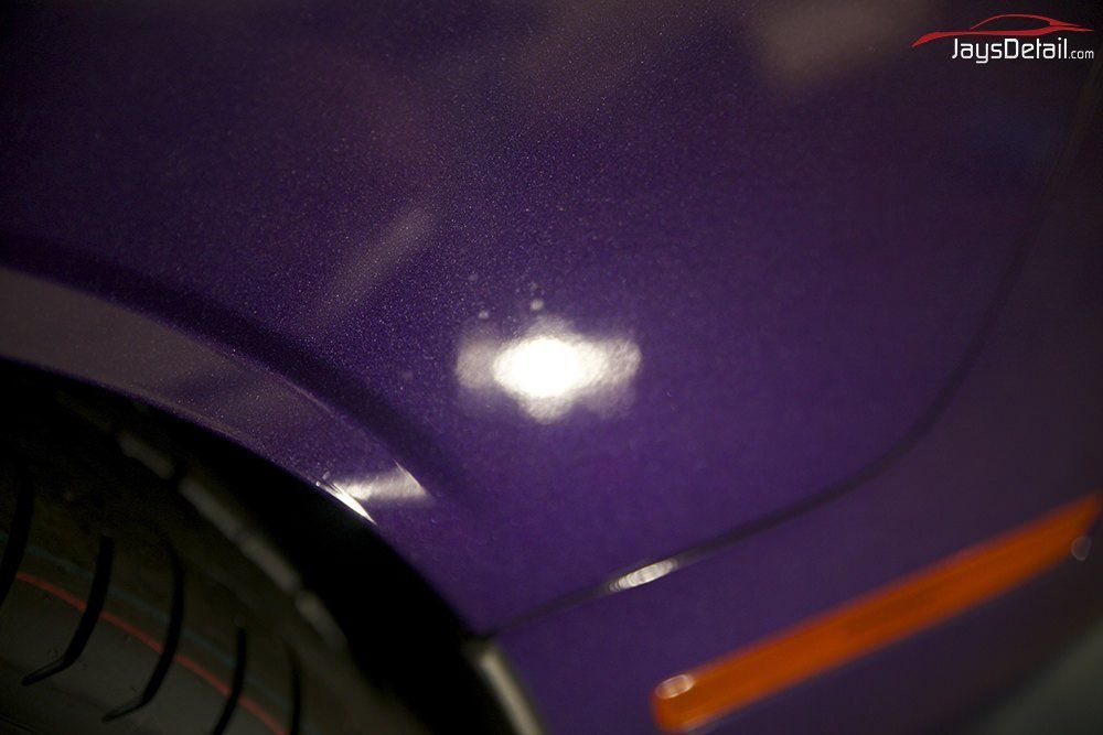Purple car panel with an orange side marker light; a tire is visible in the foreground.