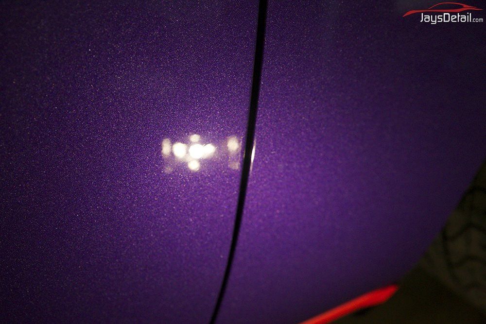 Close-up of a purple car door with metallic flake, showcasing reflection and door seam.