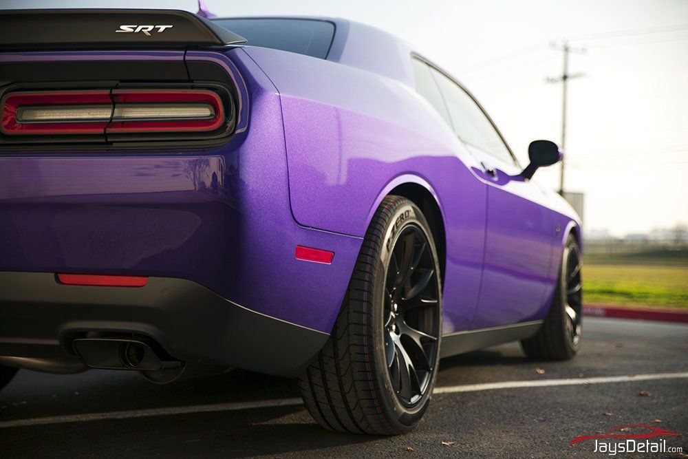 Purple Dodge Challenger SRT sports car, black wheels, parked on pavement.