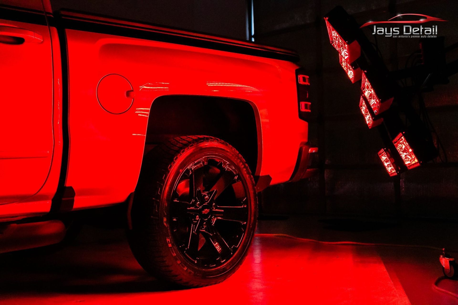 Red-lit pickup truck with black wheels, illuminated by a red light source.