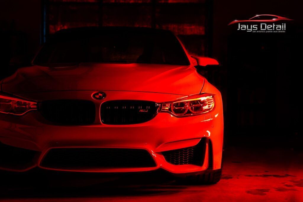 Red-lit BMW car front, showcasing its headlights and grille; Jay's Detail logo in top right.