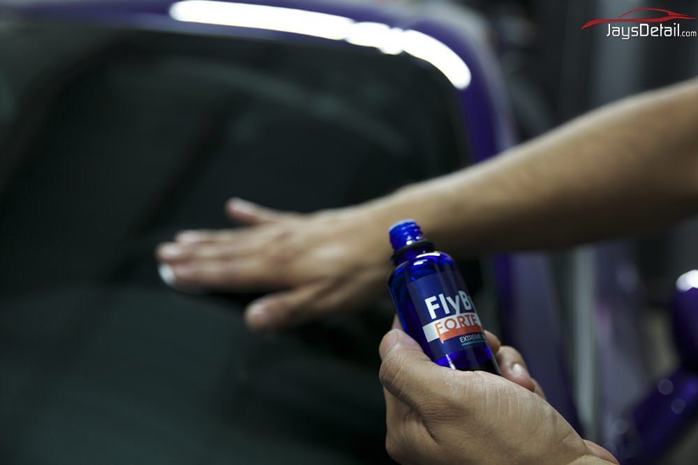 A person applying a detailing product to a car window.