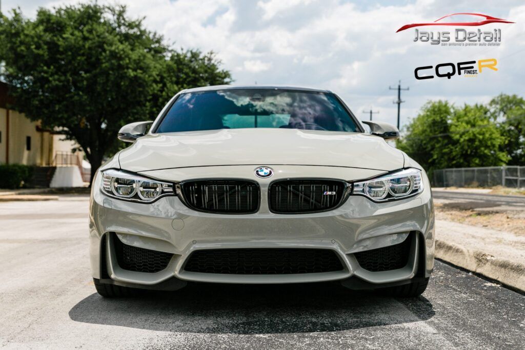 White BMW M3 car, front view, parked outdoors. Black front grill.