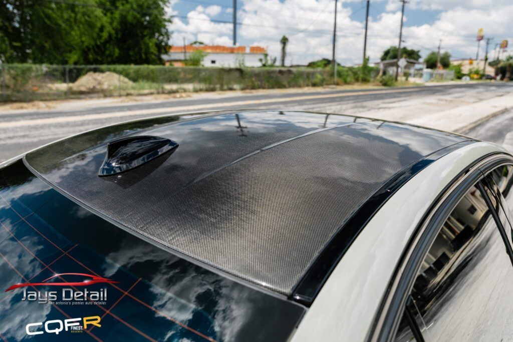 Carbon fiber car roof with an antenna, black and gray.