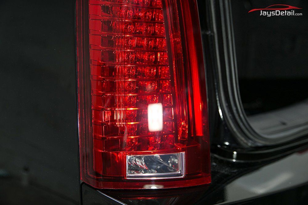 Close-up of a bright red Cadillac taillight. The light is rectangular with a square at the bottom.