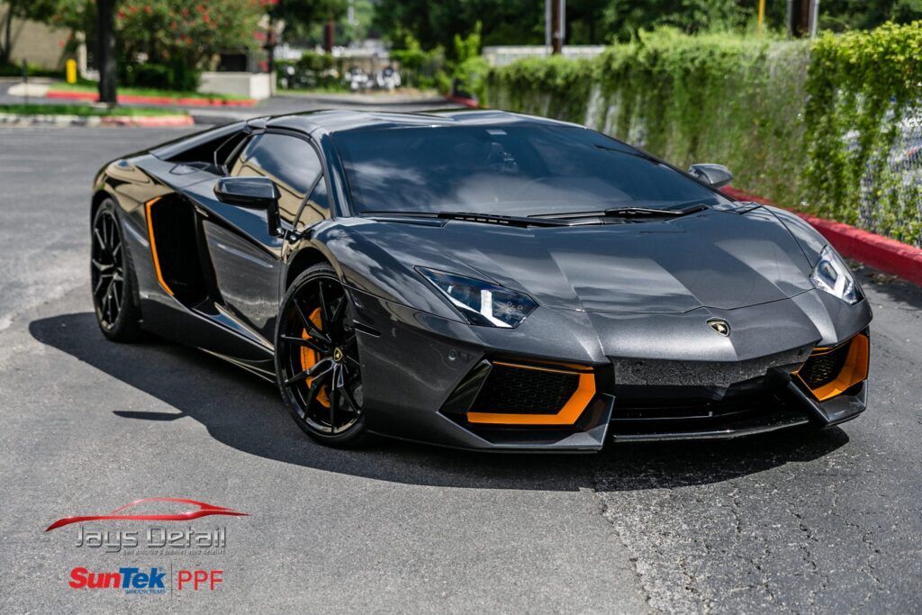 Black Lamborghini sports car with orange accents parked outdoors.
