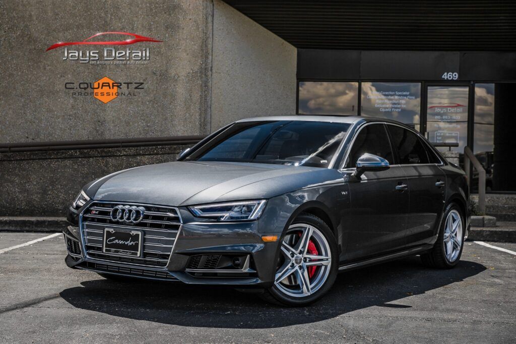 Gray Audi sedan parked in front of a building; silver rims, red brake calipers.