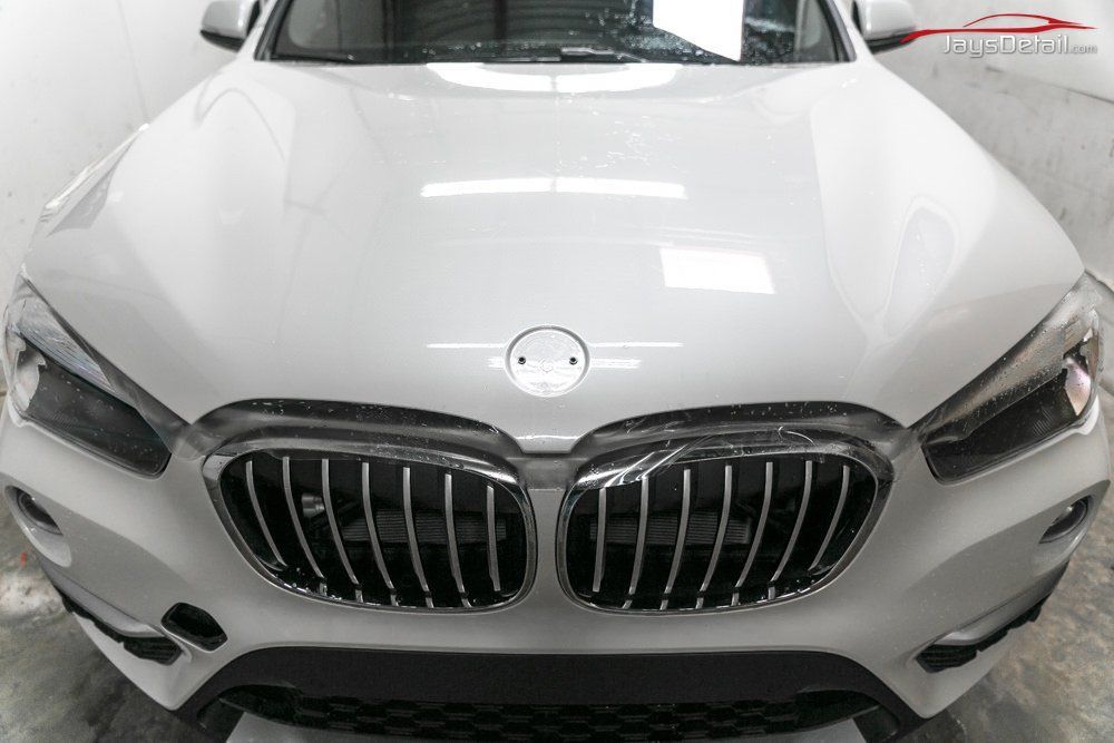 White BMW SUV front view with chrome grille and logo.