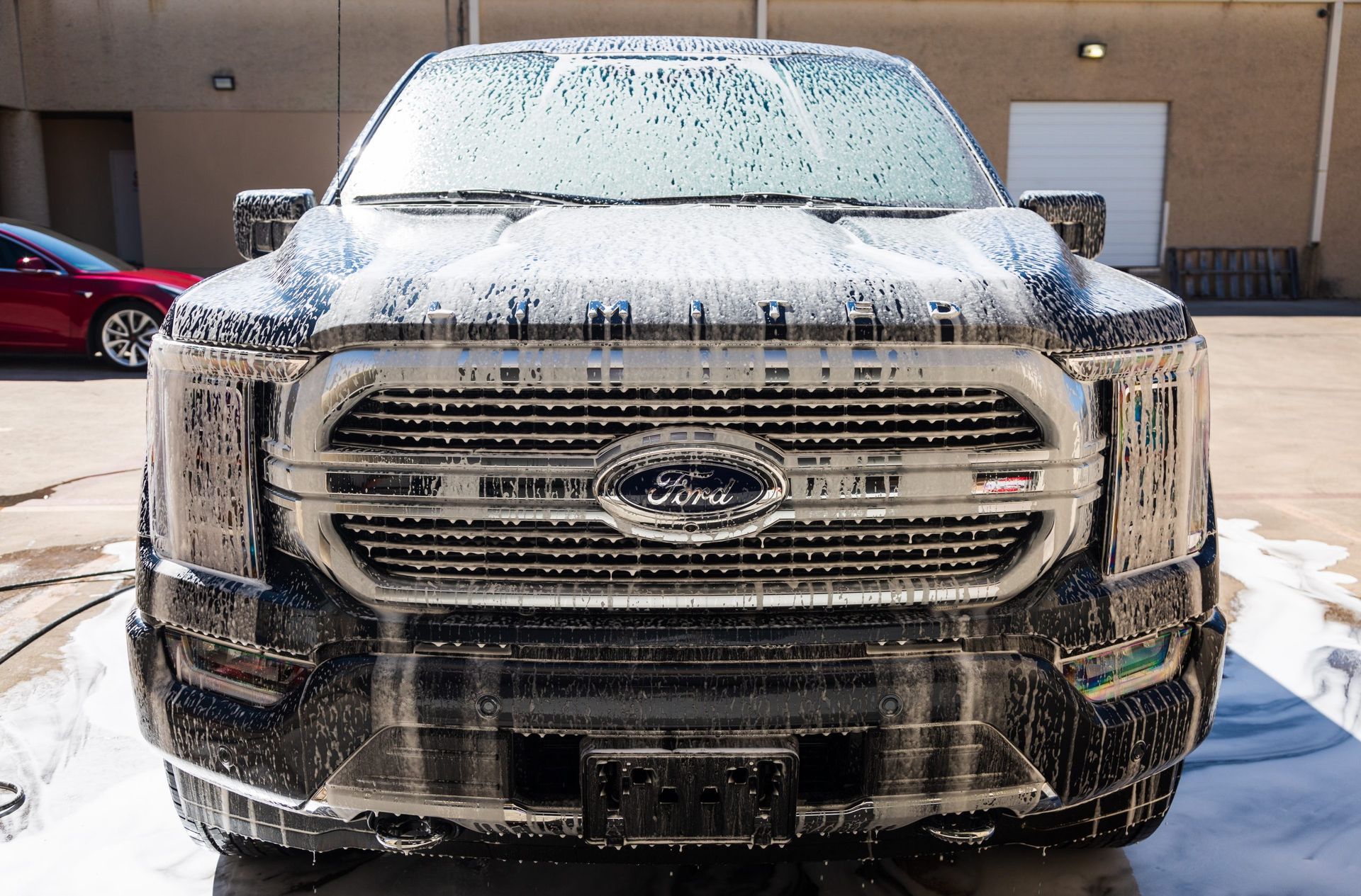 Ford truck covered in white foam at a car wash.