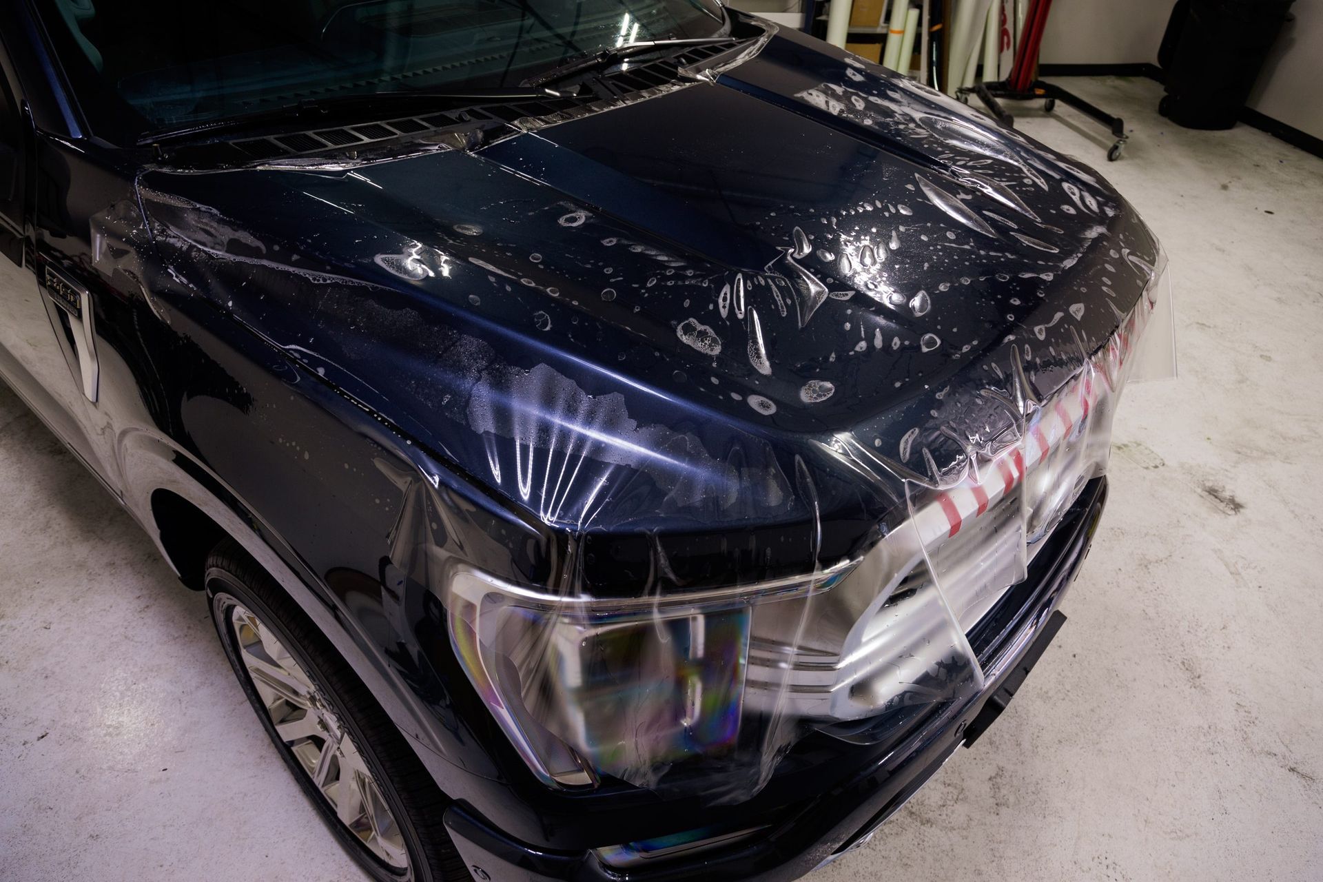 Dark blue car hood covered in clear protective film.