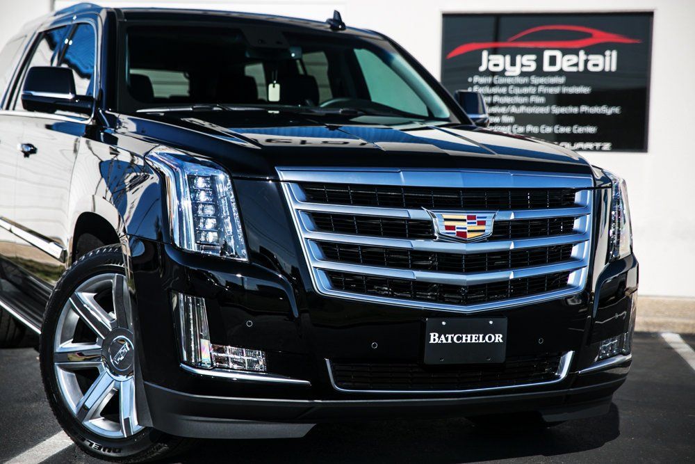Black Cadillac Escalade SUV parked in front of a detailing shop
