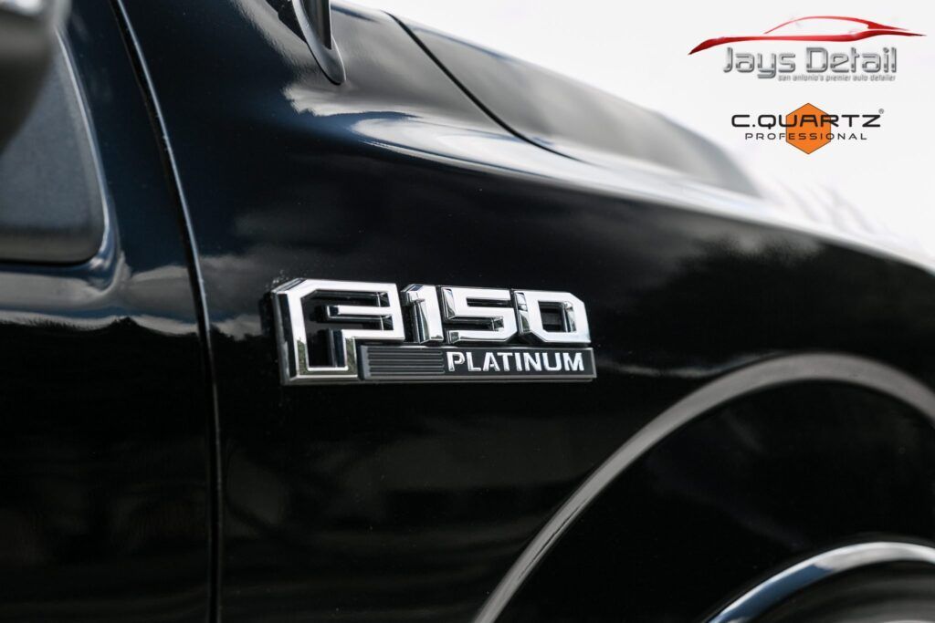 Close-up of a shiny black Ford F-150 Platinum truck fender with chrome badging.