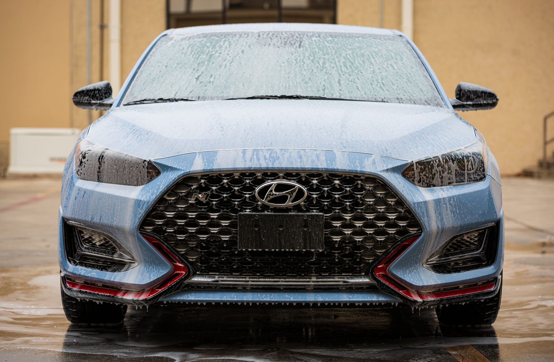 Blue Hyundai car covered in foam, front view.