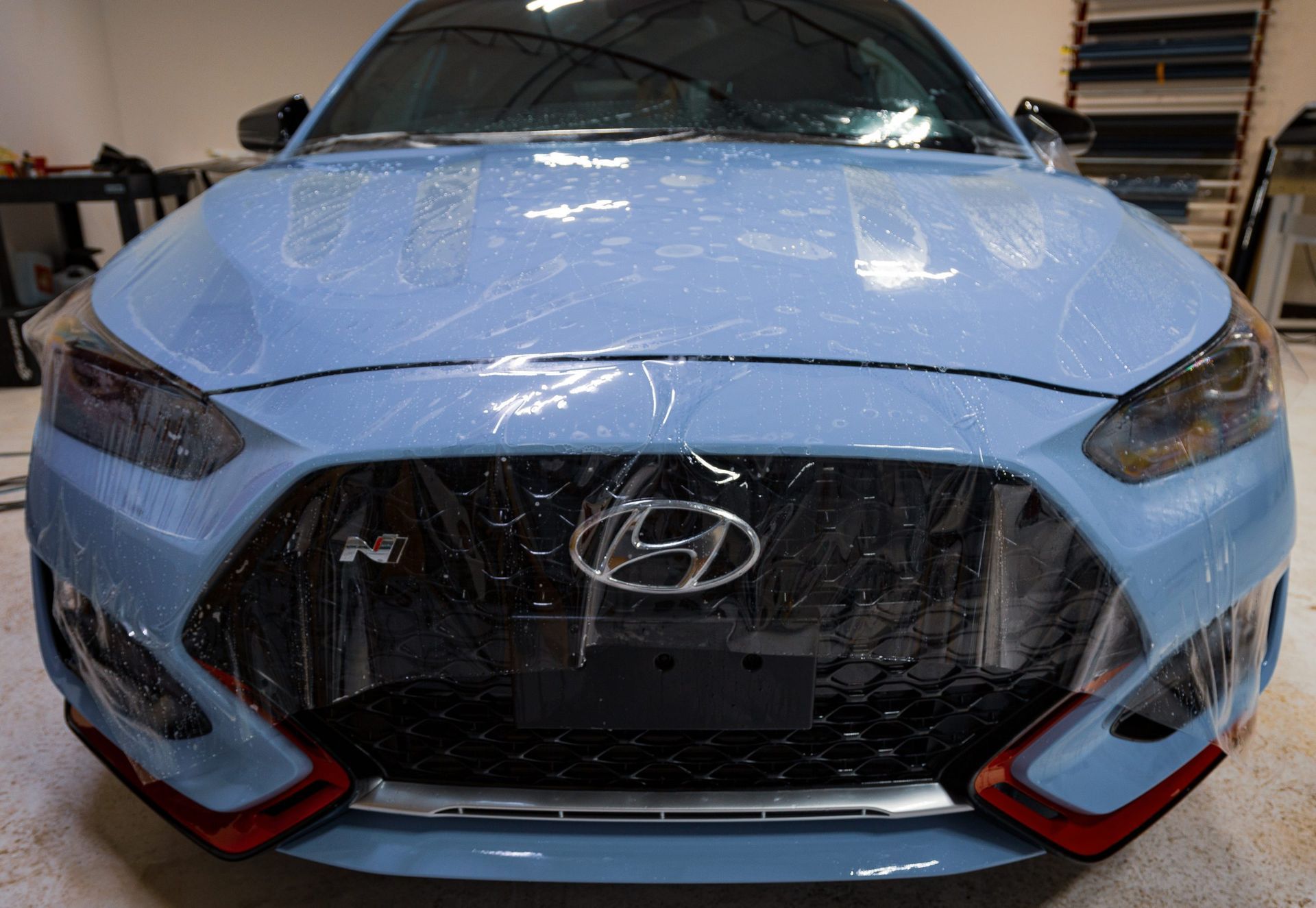 Blue Hyundai car with protective film on the front, indoors.