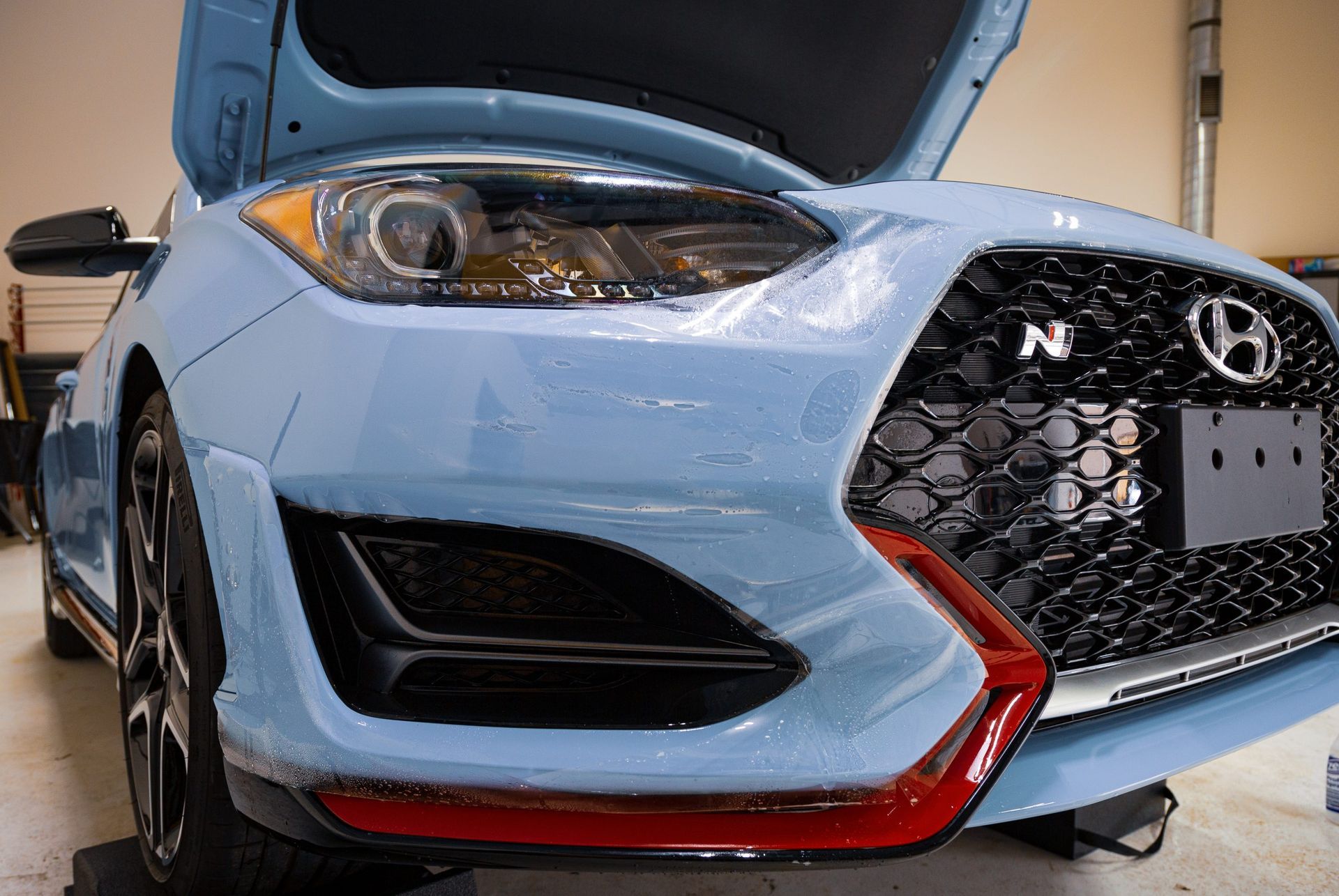 Blue Hyundai Veloster N car with open hood, black grill, and red accents.