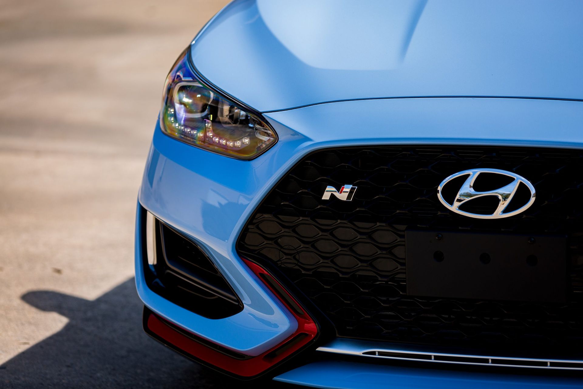 Close-up of a blue Hyundai Veloster N car's front with a black grille and red accents.
