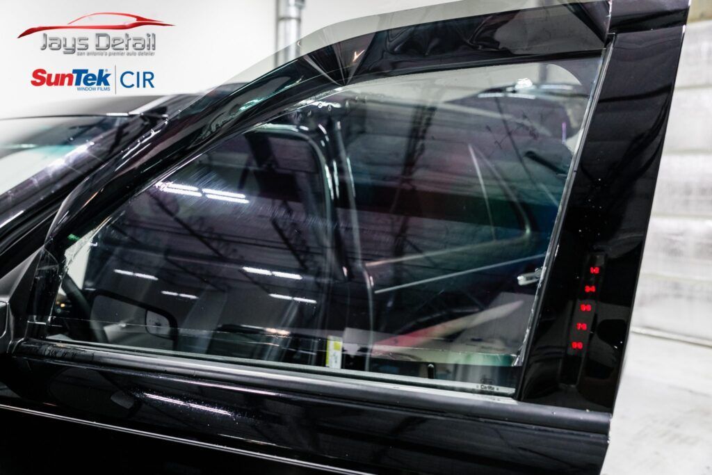 Black car door with tinted windows, side view, showing buttons and interior.