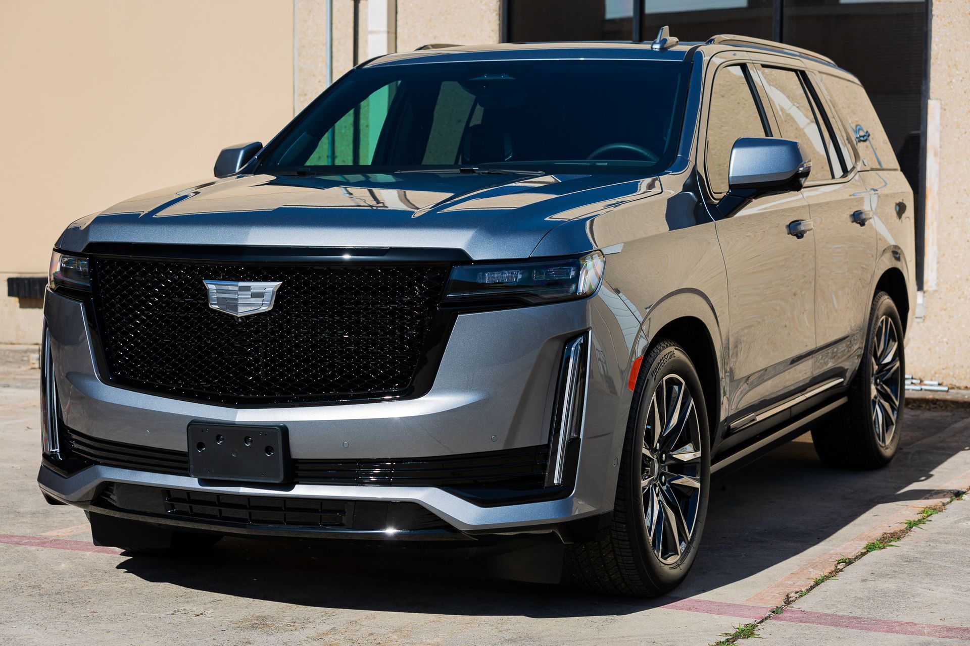 Gray Cadillac Escalade SUV parked outside, angled view. Black grille, wheels, and accents.
