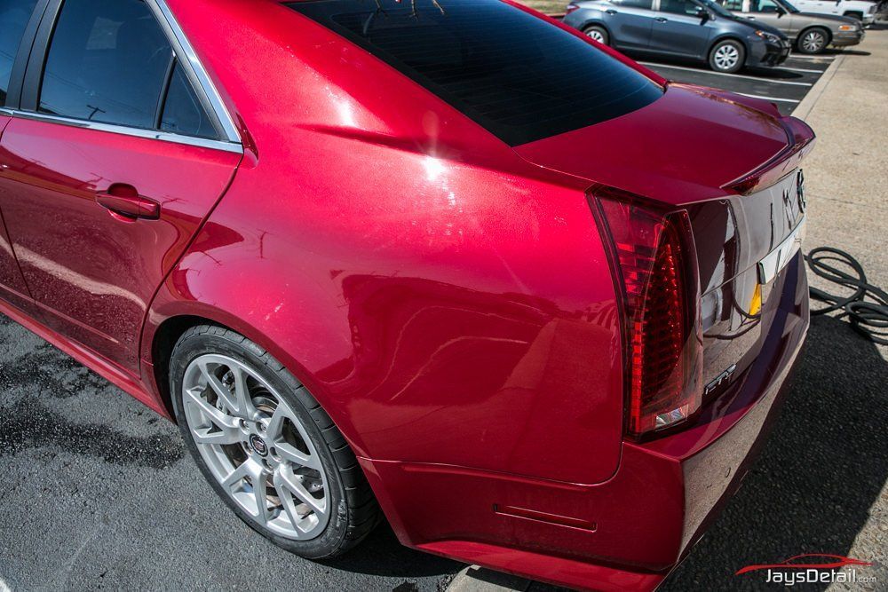Red Cadillac sedan, parked, with taillight detail and metallic paint shine.