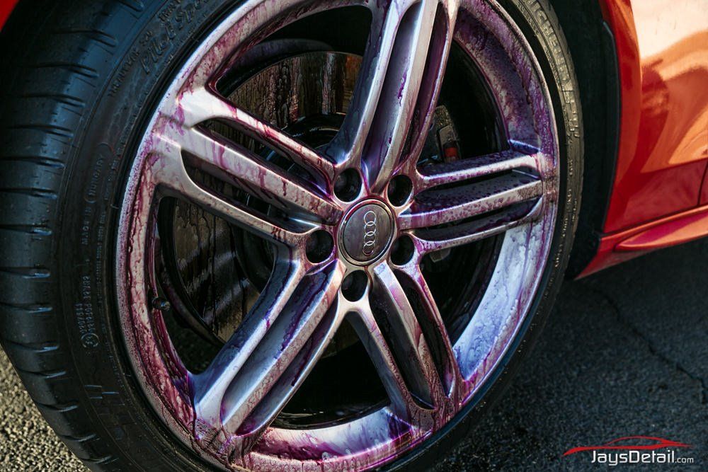 A close-up of an Audi car wheel, with a purple-colored iron remover on the rim.