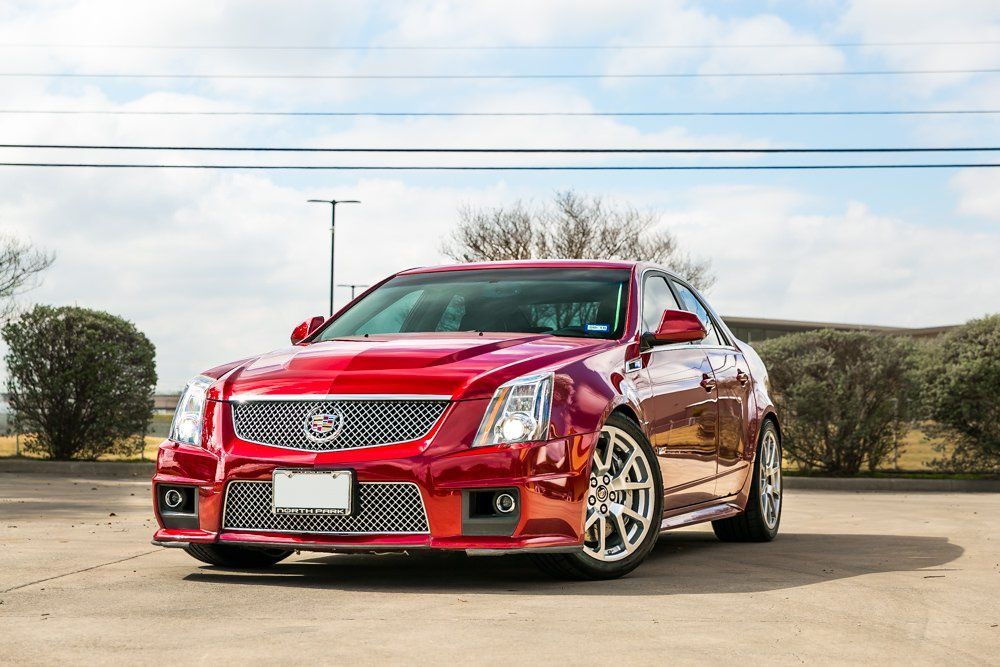Red Cadillac CTS-V sedan with silver wheels parked outside on a sunny day.