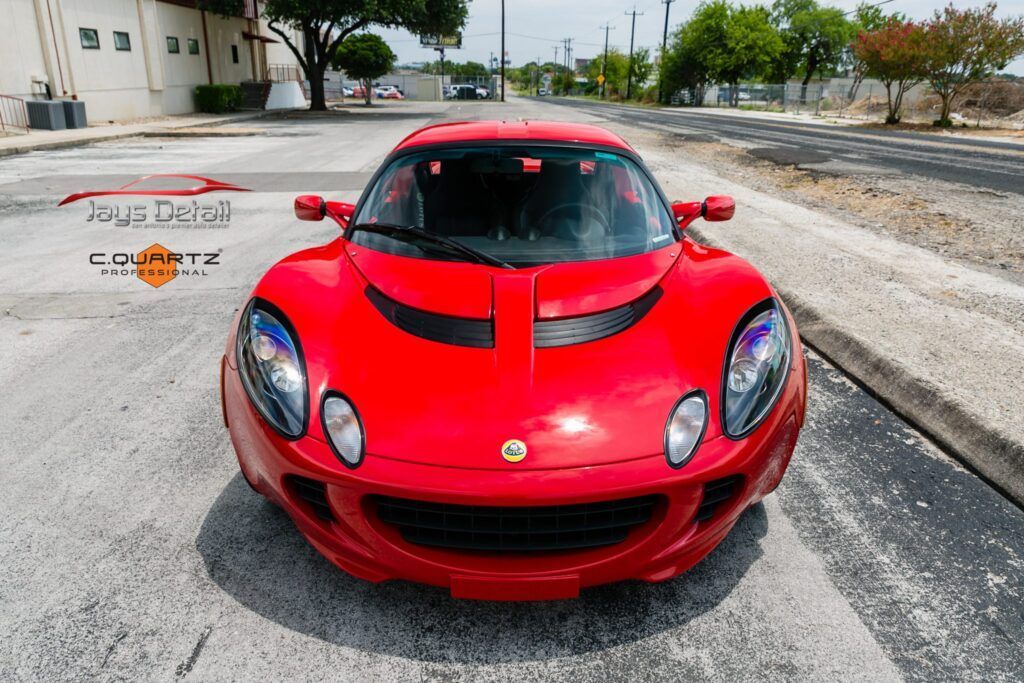 Red Lotus sports car parked on asphalt, front view.