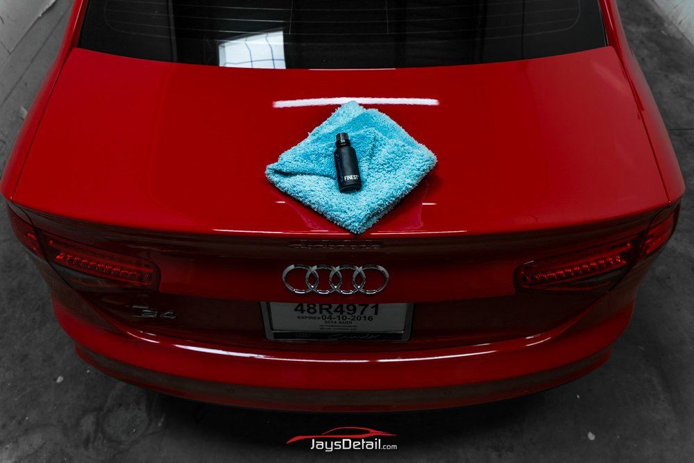 Red Audi sedan trunk with cleaning product and cloth.