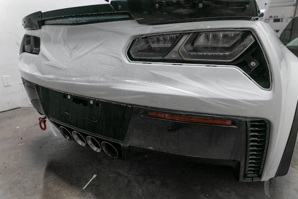 White car headlight, angled shot, part of car body visible.