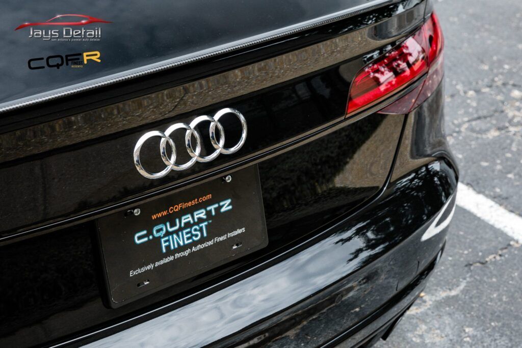 Black Audi car rear with chrome logo and license plate.