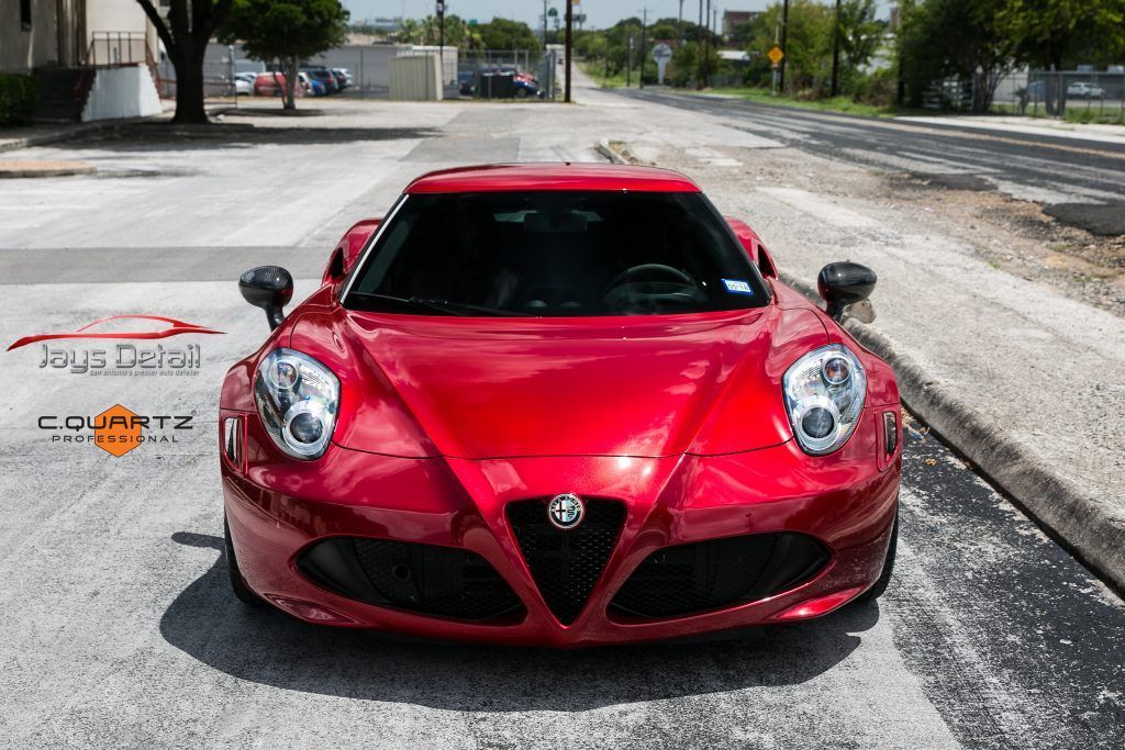 Red Alfa Romeo 4C sports car parked on an asphalt road; front view.