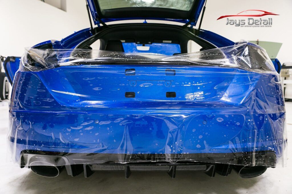 Blue car rear end covered with clear protective film.