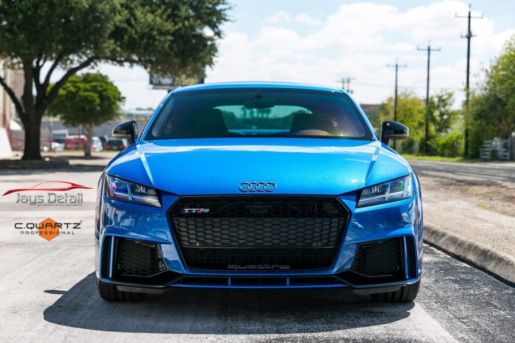 Blue Audi TT RS sports car parked on a road, front view.