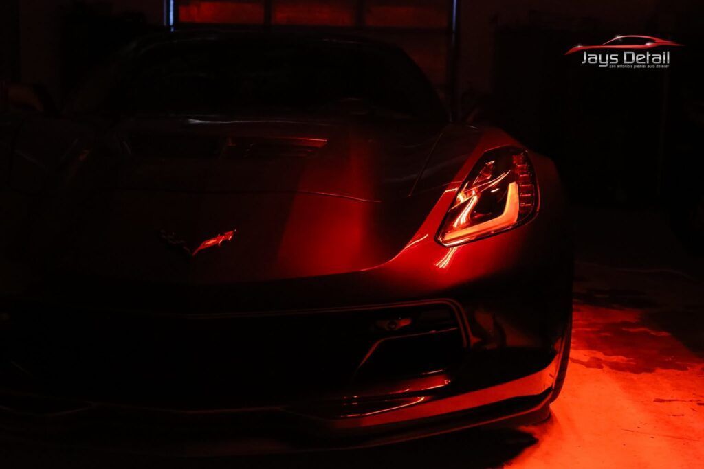 Red sports car with headlights illuminated in a dark garage.