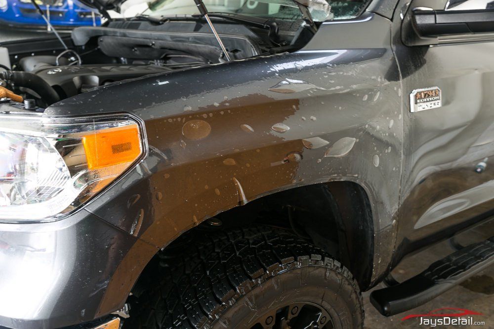 Gray truck fender with clear film applied, wet with water. The hood is open.