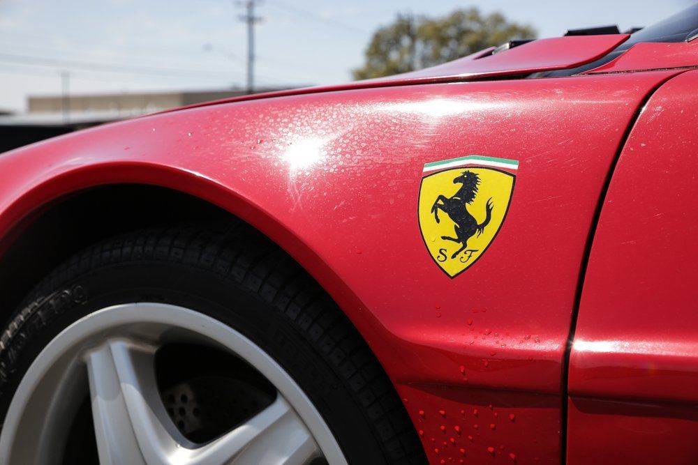 Red Ferrari car with the iconic yellow and black shield logo on the fender.