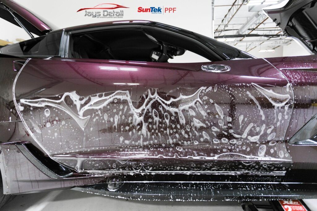 Car door with protective film being applied, covered in soapy water.