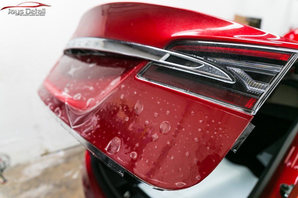 Red car tail light with water droplets, protective film applied.